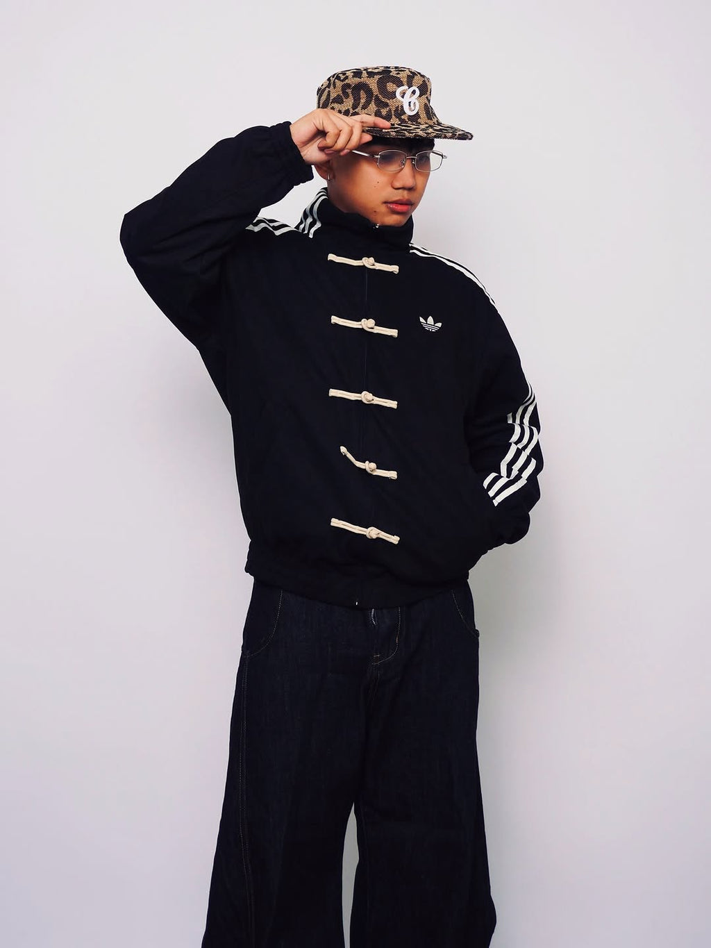 Person wearing a Black Chinese New Year Tang jacket sweater with white stripes and buttons, paired with dark pants