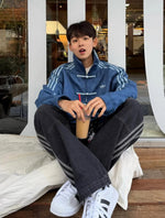 Person sitting on a bench wearing an Premium Navy Blue CNY Jacket - Northly Exclusive
, holding a drink.