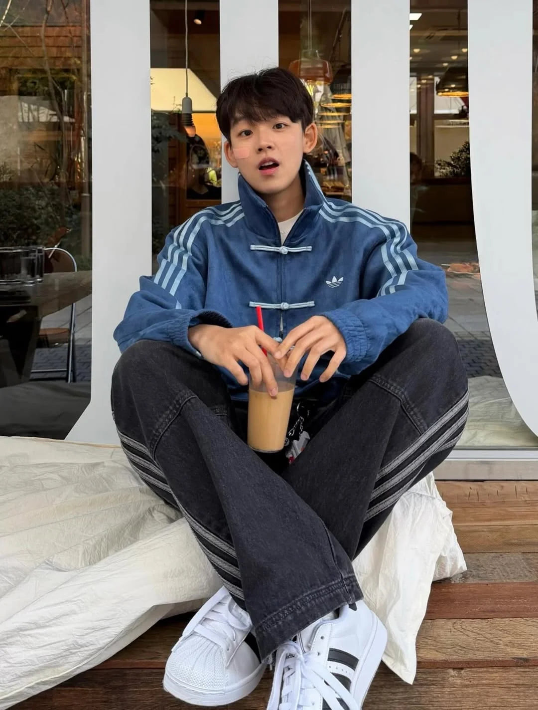 Person sitting on a bench wearing an Premium Navy Blue CNY Jacket - Northly Exclusive
, holding a drink.