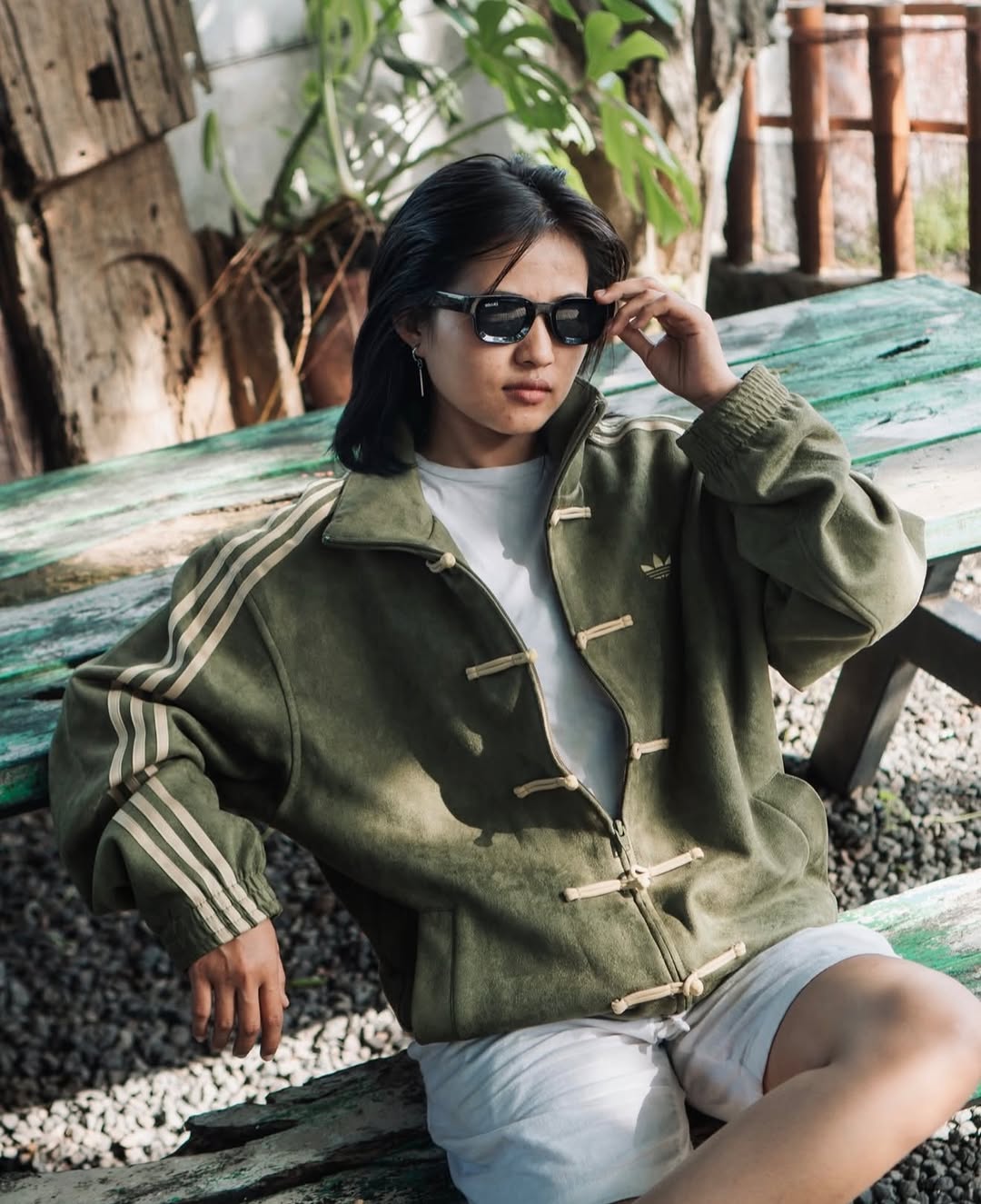 Indian woman styling the earthy Olive Green Chinese New Year Jacket by Northly with dark trousers for a modern streetwear outfit