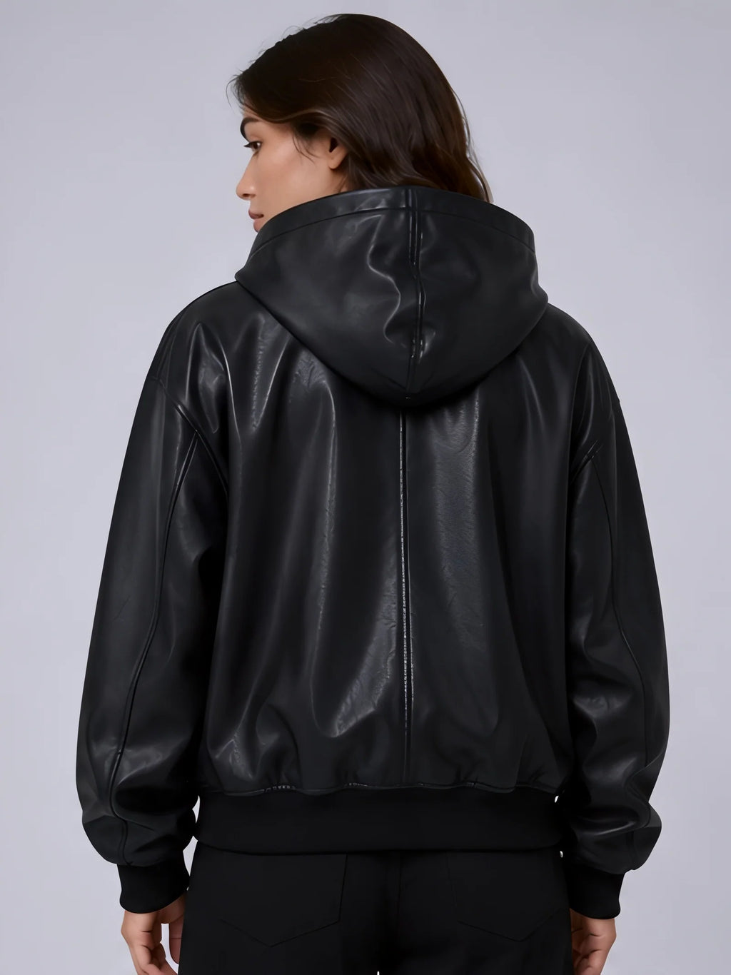 Person wearing a black leather bomber jacket on a plain background