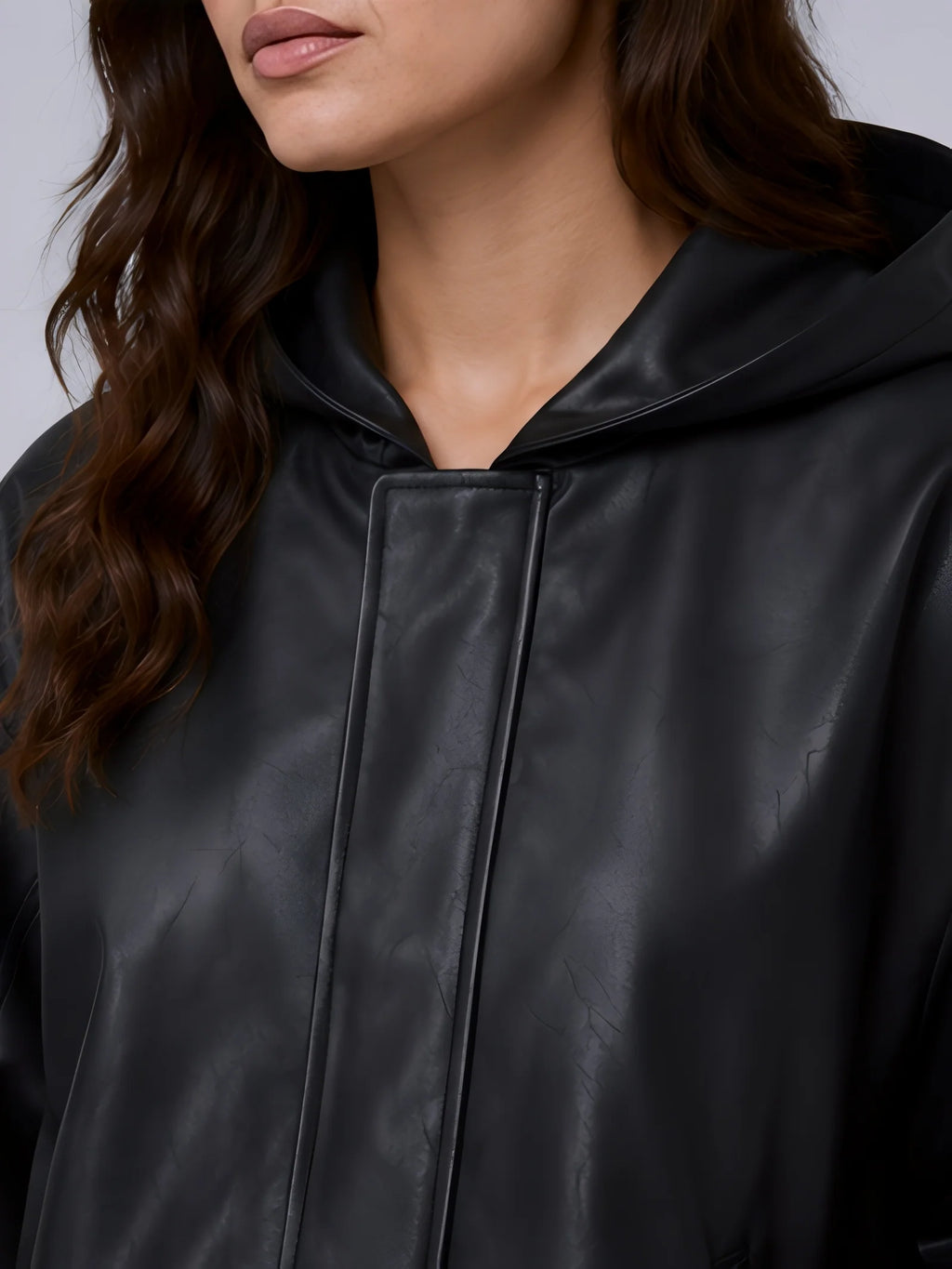 Close-up of a person wearing a black hooded jacket with a plain background