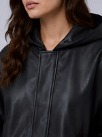 Close-up of a person wearing a black hooded jacket with a plain background