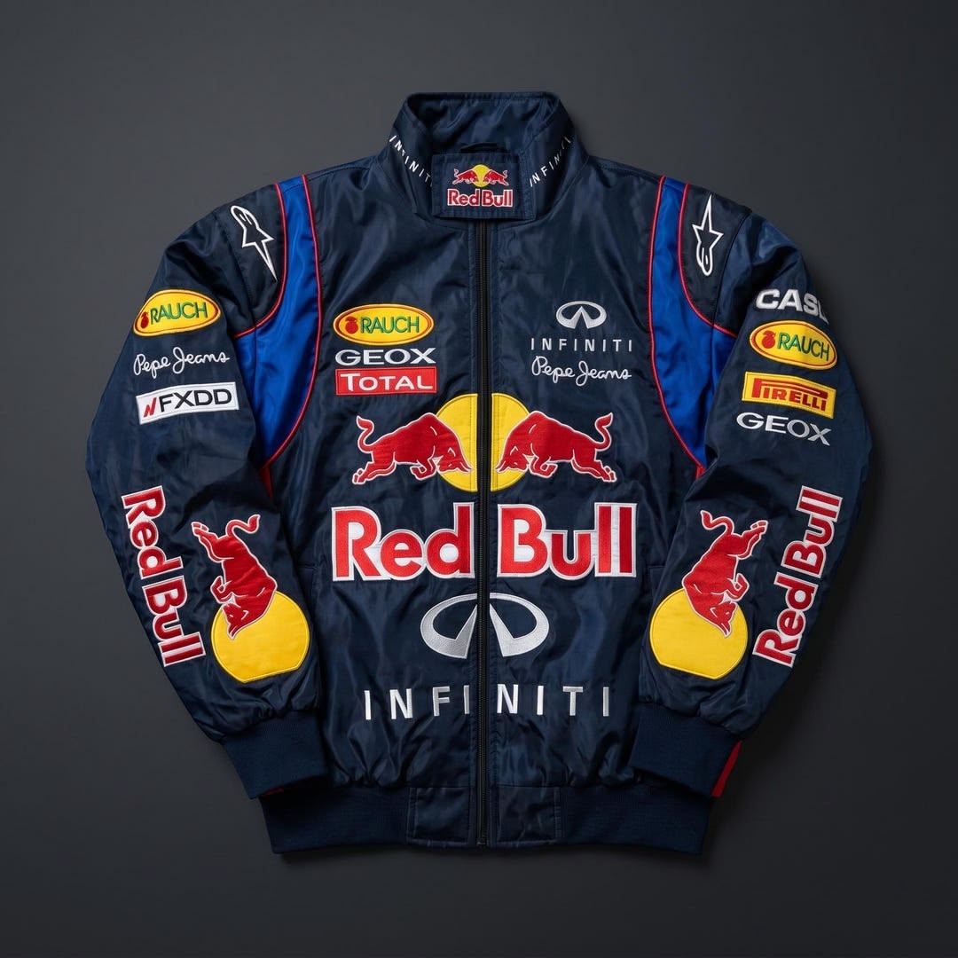 A navy blue Red Bull Racing parchute bomber jacket with multiple sponsor logos including Red Bull, Infiniti, GeoX, and Pepsijermons, displayed flat against a dark gray background.